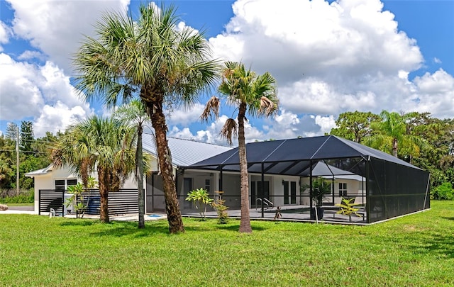 rear view of property featuring a lanai and a lawn