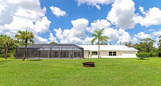 back of property featuring glass enclosure and a lawn