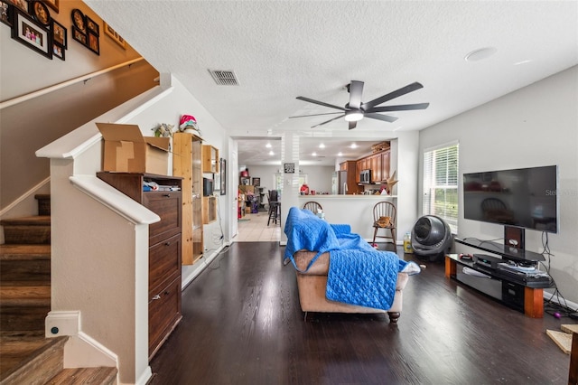 living room with ceiling fan, wood-type flooring, and a textured ceiling