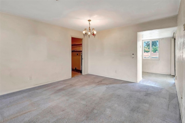 carpeted empty room featuring an inviting chandelier