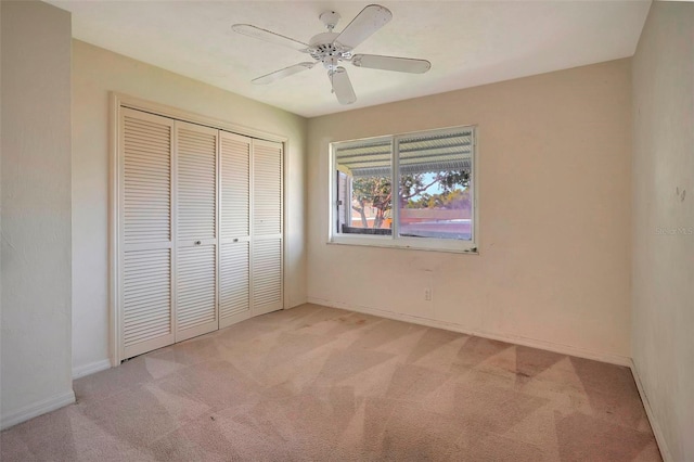 unfurnished bedroom with ceiling fan, a closet, and light carpet