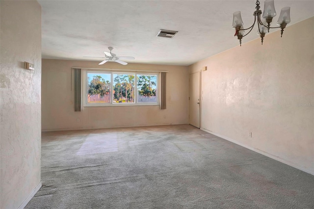 carpeted spare room featuring ceiling fan with notable chandelier