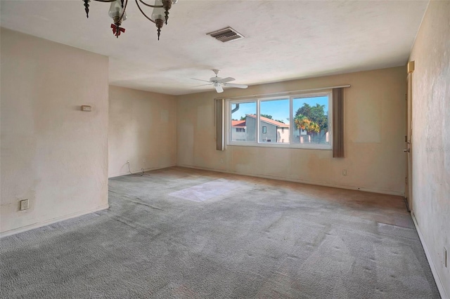 carpeted empty room with ceiling fan with notable chandelier