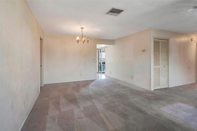 carpeted spare room featuring an inviting chandelier