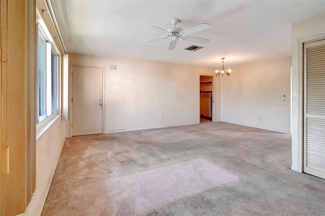 carpeted spare room with ceiling fan with notable chandelier