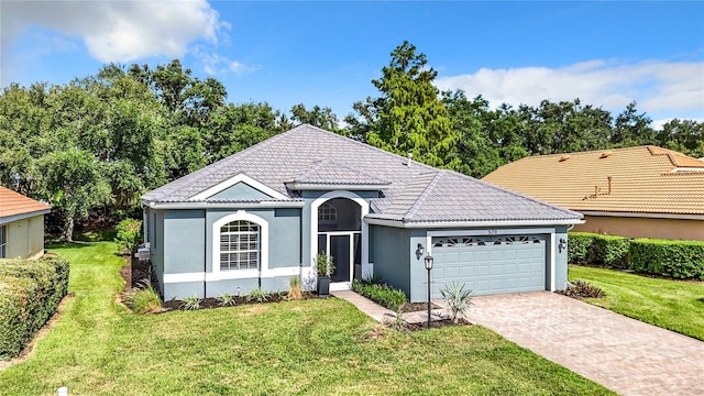 view of front of property featuring an attached garage, a tiled roof, decorative driveway, stucco siding, and a front yard