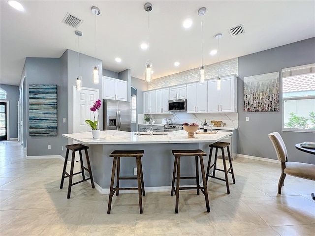 kitchen featuring hanging light fixtures, appliances with stainless steel finishes, a spacious island, and visible vents