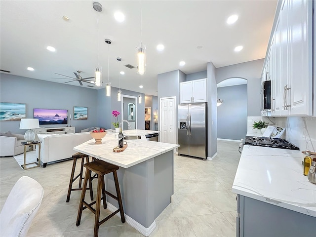 kitchen featuring hanging light fixtures, white cabinets, a sink, an island with sink, and stainless steel fridge with ice dispenser