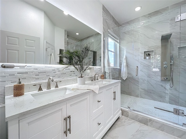 bathroom featuring a stall shower, marble finish floor, a sink, and double vanity