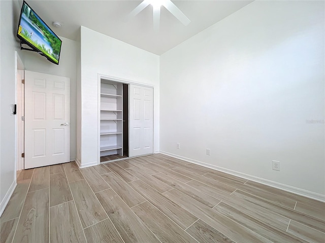 unfurnished bedroom with wood tiled floor, baseboards, ceiling fan, and a closet