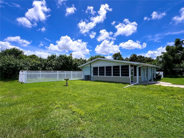 rear view of property with central AC and a lawn