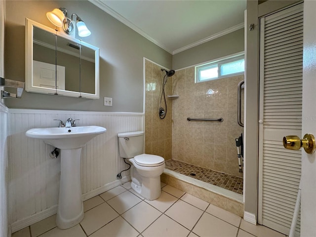 bathroom featuring toilet, crown molding, tiled shower, and tile patterned floors