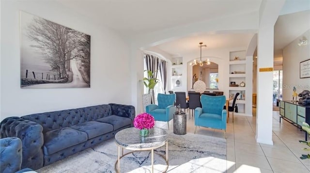 living room with built in shelves, a notable chandelier, and light tile patterned flooring