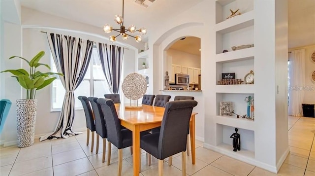 dining room with built in shelves, a notable chandelier, and light tile patterned floors