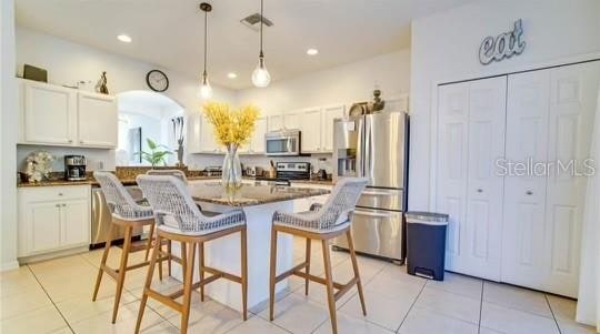 kitchen featuring light tile patterned flooring, a kitchen breakfast bar, stainless steel appliances, and white cabinets