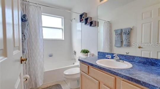 full bathroom with vanity, shower / bath combo with shower curtain, and toilet