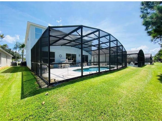 rear view of property featuring a patio, a lawn, and a lanai