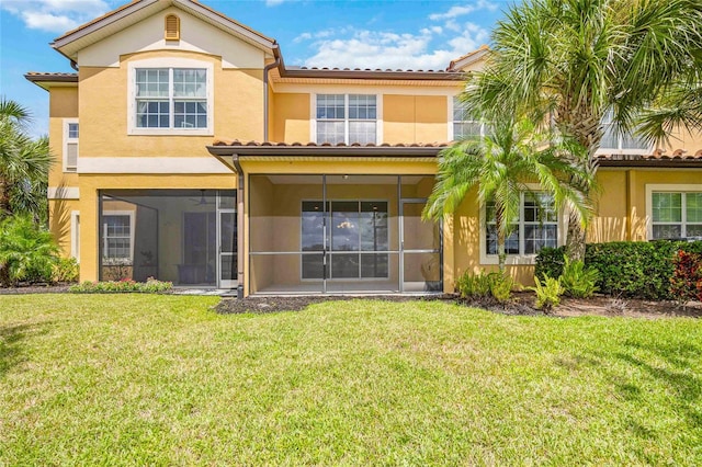 rear view of property featuring a yard, a sunroom, and stucco siding