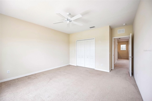 unfurnished bedroom featuring ceiling fan, a closet, and light carpet