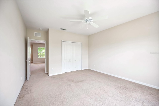 unfurnished bedroom with ceiling fan, light carpet, and a closet