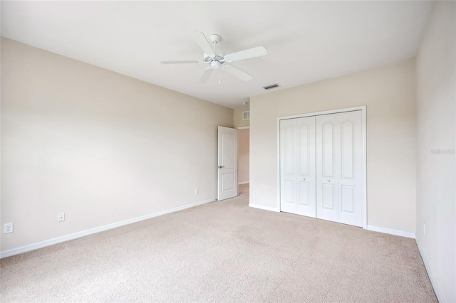 unfurnished bedroom featuring ceiling fan, light colored carpet, and a closet