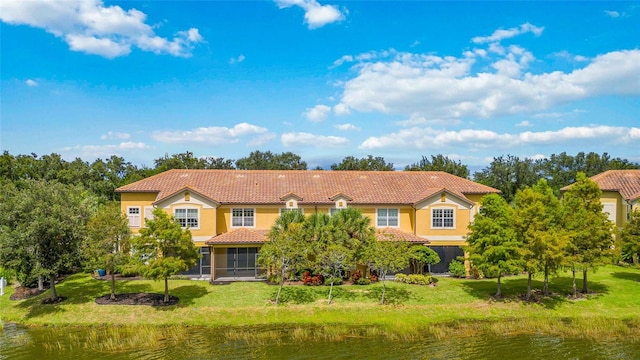 view of front of property with a tile roof, stucco siding, a water view, a front yard, and a sunroom