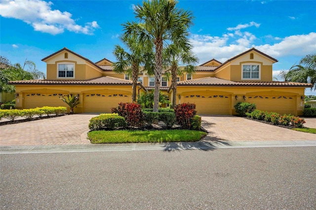 mediterranean / spanish house featuring decorative driveway, a tiled roof, and stucco siding