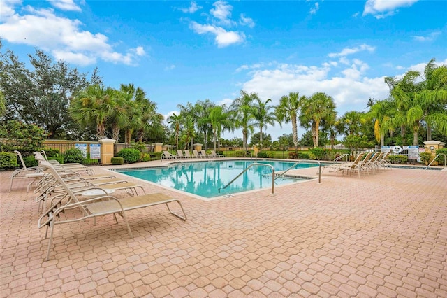 pool with a patio and fence