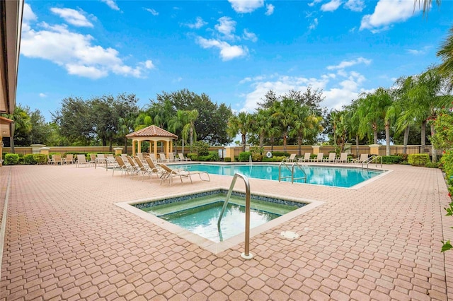 community pool featuring a gazebo, a patio area, fence, and a hot tub