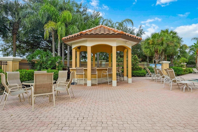 view of patio featuring outdoor dry bar and fence