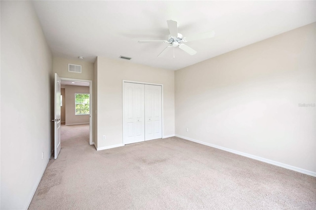 unfurnished bedroom with baseboards, visible vents, a closet, and light colored carpet