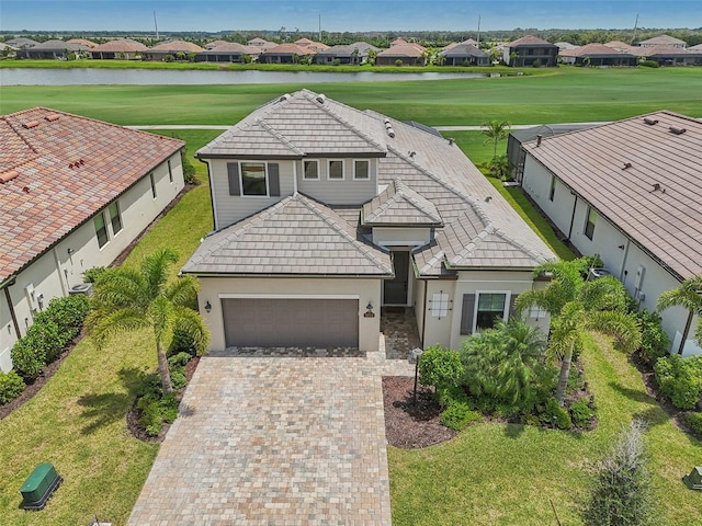 view of front of property with a garage, a water view, and a front lawn