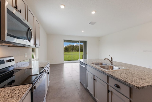 kitchen featuring sink, appliances with stainless steel finishes, an island with sink, light tile patterned floors, and gray cabinets