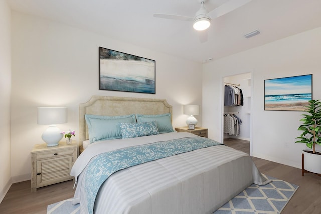 bedroom featuring a spacious closet, light hardwood / wood-style flooring, ceiling fan, and a closet