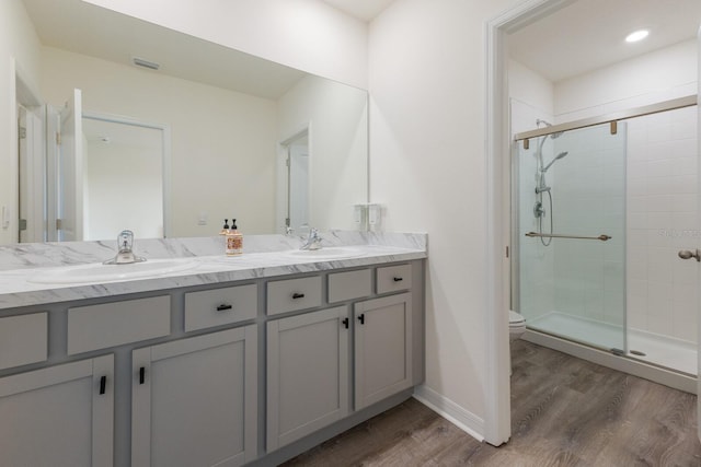 bathroom with hardwood / wood-style floors, toilet, vanity, and a shower with shower door