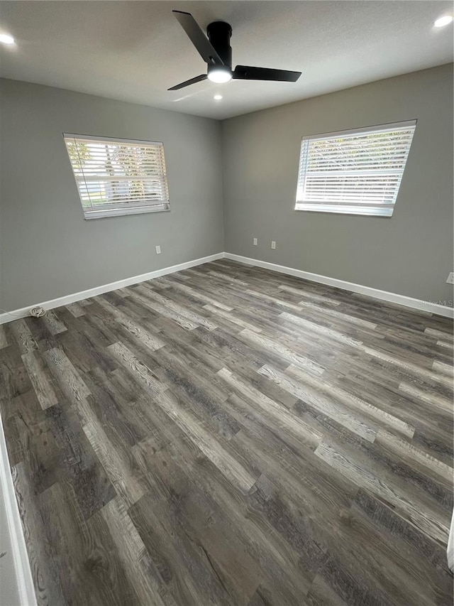 unfurnished room featuring dark wood-type flooring, ceiling fan, and plenty of natural light