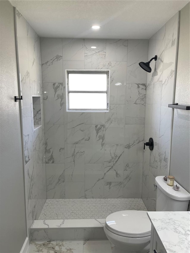 bathroom featuring vanity, toilet, and a tile shower