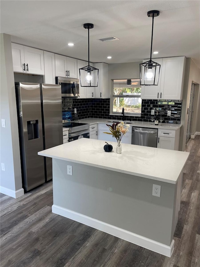 kitchen with white cabinetry, appliances with stainless steel finishes, a kitchen island, and hanging light fixtures