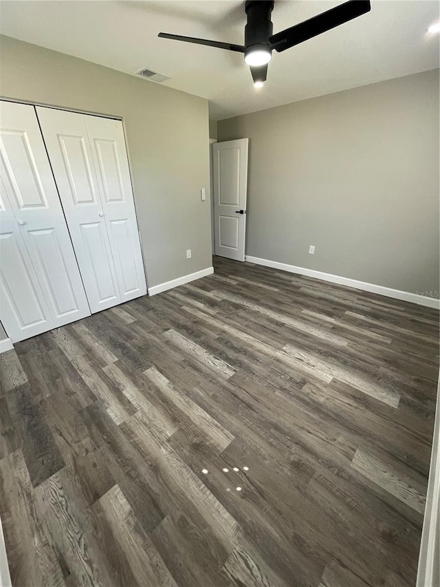 unfurnished bedroom with dark wood-type flooring, a closet, and ceiling fan