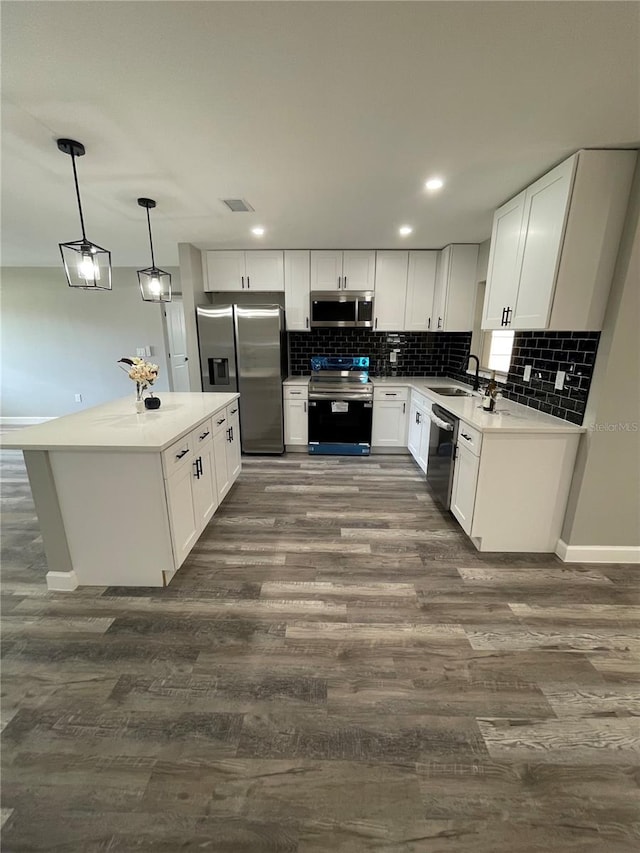 kitchen featuring white cabinets, dark hardwood / wood-style flooring, sink, pendant lighting, and stainless steel appliances