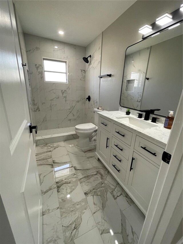 bathroom with vanity, a tile shower, and toilet