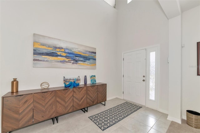 foyer with baseboards, light tile patterned floors, and a high ceiling