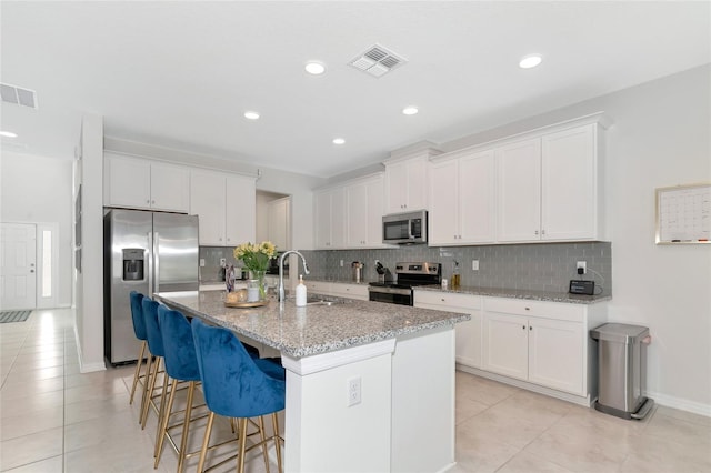 kitchen featuring a sink, white cabinetry, a center island with sink, and stainless steel appliances