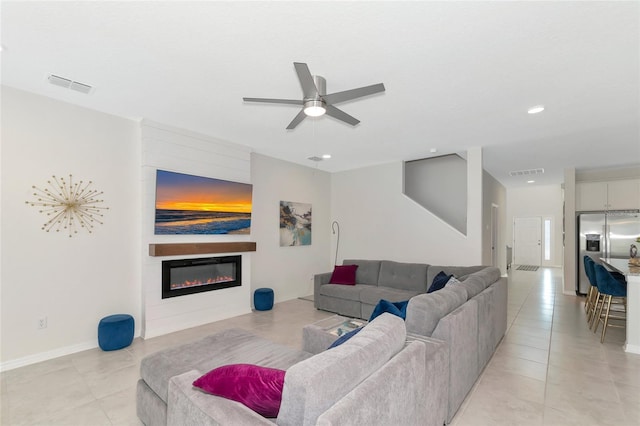 tiled living room with ceiling fan and a large fireplace