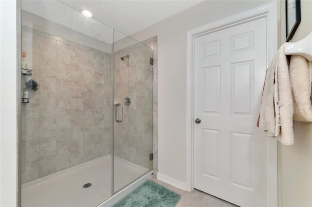 bathroom featuring baseboards, tile patterned floors, and a stall shower