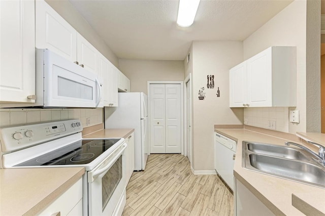 kitchen with light wood-type flooring, white appliances, white cabinetry, backsplash, and sink