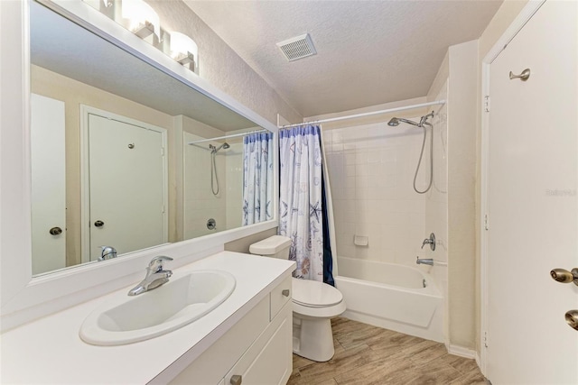 full bathroom featuring a textured ceiling, vanity, shower / bath combination with curtain, wood-type flooring, and toilet