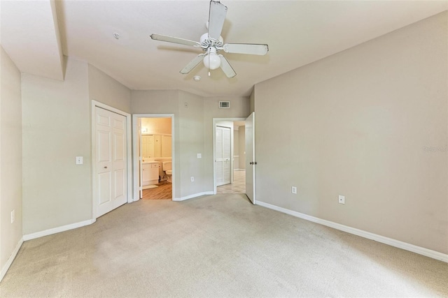 unfurnished bedroom featuring ensuite bath, light carpet, and ceiling fan