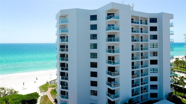 view of building exterior with a beach view and a water view