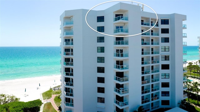 view of building exterior with a beach view and a water view